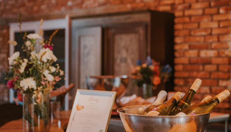 Bar-Tresen. Es stehen eine Schale mit gekühlten Weinflaschen und ein Bilderrahmen mit schwer-lesbarem Text oben drauf.