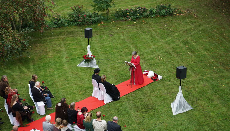 Eine Hochzeits auf einer Wiese. Ein roter Teppich ist ausgelegt. Bild wurde von einer fliegenden Drohne aufgenommen.