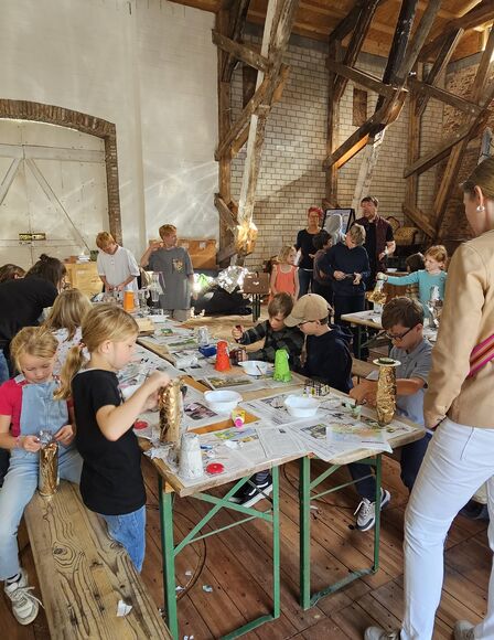 Kinder-Bastel-Event in Scheune, es sind mehrere Kinder und ein paar wenige Erwachsene zu sehen