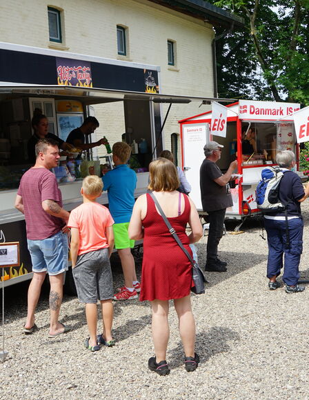 Soft-Eis und Grill Wagen vor Scheune, im Hintergrund ein Wrap-Stand, AN jedem STand stehen Leuet an