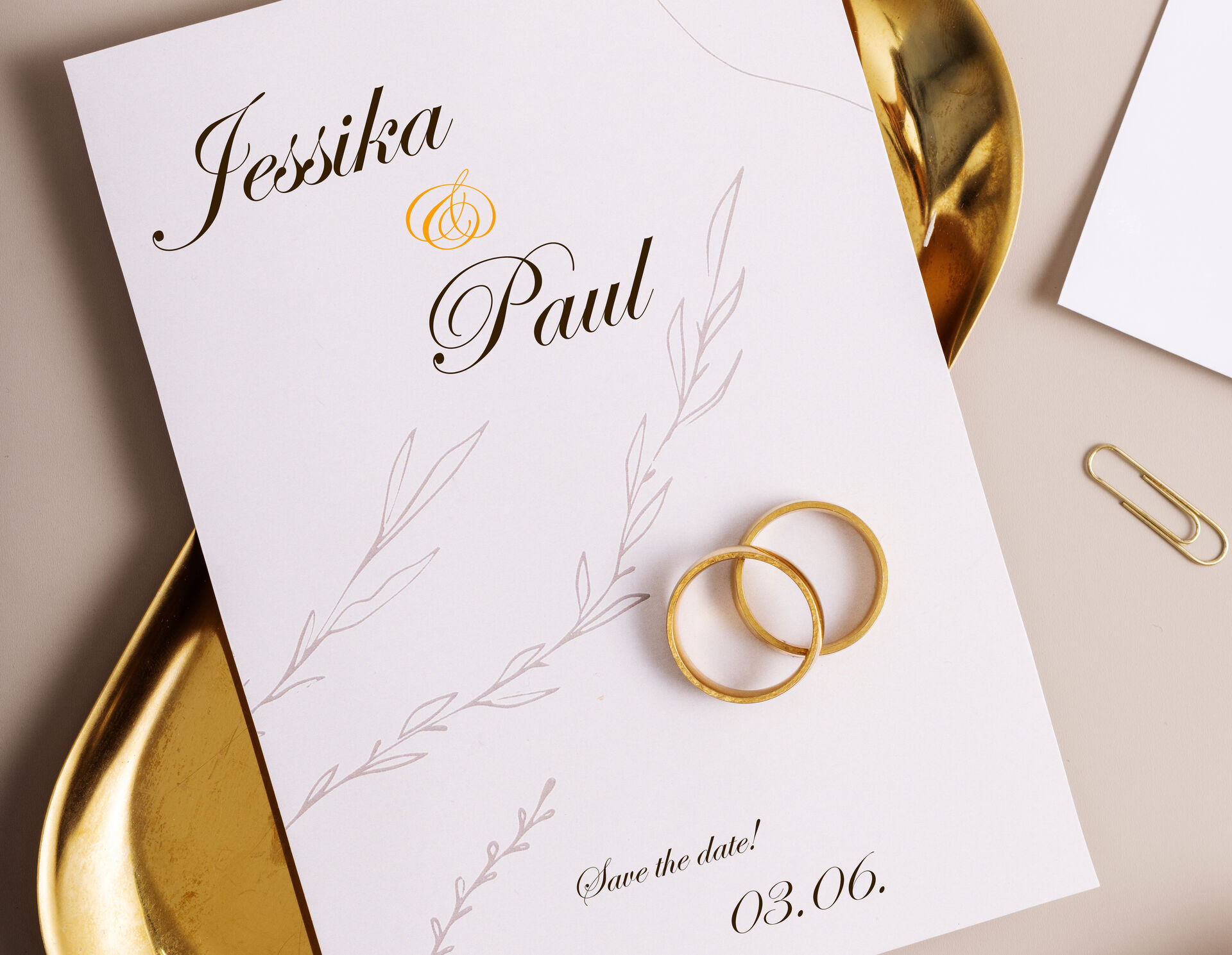 Eine Hochzeitseinladung zum dritten Juni. Es leigen zwei goldene Ringe auf der Karte.
