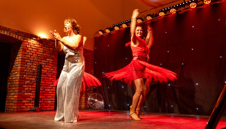 Stephanie Steup klatschend und rufend auf Bühne, hinter und neben ihre je eine Junge Dame