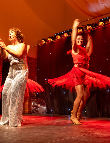 Stephanie Steup klatschend und rufend auf Bühne, hinter und neben ihre je eine Junge Dame