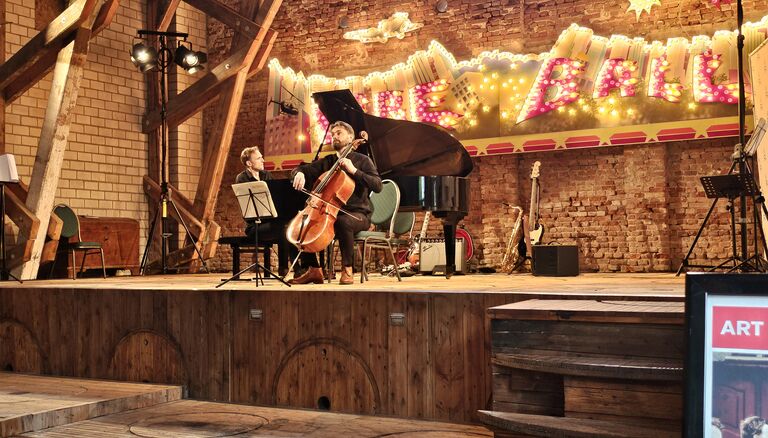 Klavier- und Cello-Spieler auf Bühne in Asmus-Petersen Scheune, im Hintergrund der Fireballs-Schriftzug