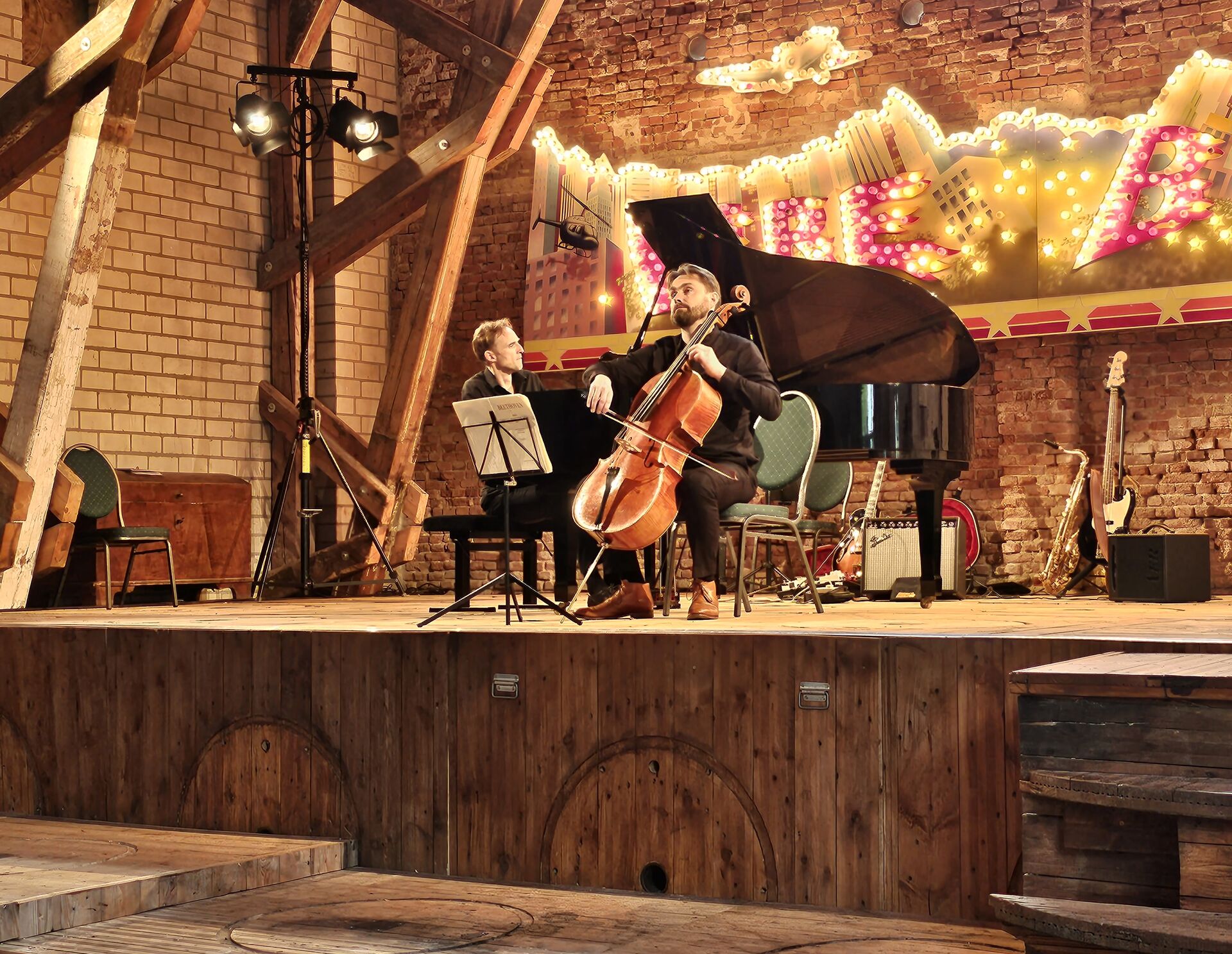 Klavier- und Cello-Spieler auf Bühne in Asmus-Petersen Scheune, im Hintergrund der Fireballs-Schriftzug