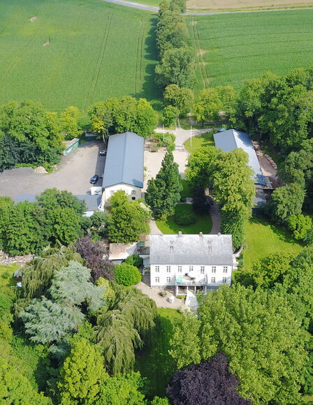 Ein Luftbild vom Wittkielhof. Das Bild ist geprägt von grünem Bras und grün belaubten Bäumen.