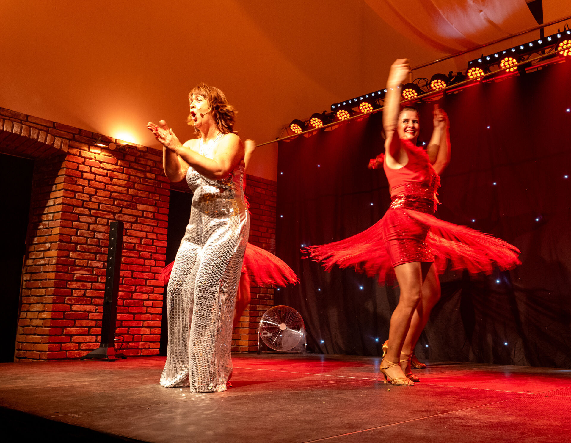 Stephanie Steup klatschend und rufend auf Bühne, hinter und neben ihre je eine Junge Dame