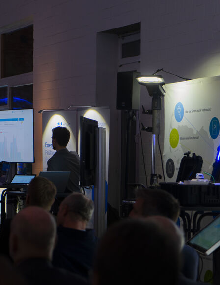 Präsentations-Stände vor einer Scheune, Sprecher und Gäste sind auf dem Bild