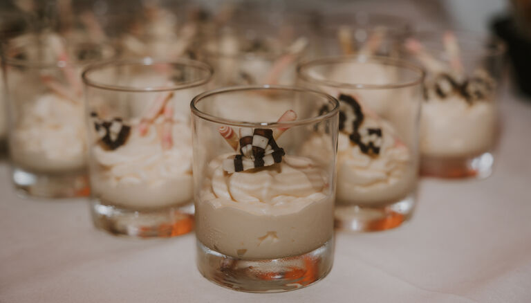 Helle Nachtisch-Creme. Zarte Schokoladen-Dekorationen liegen auf den Creme-Häufchen.