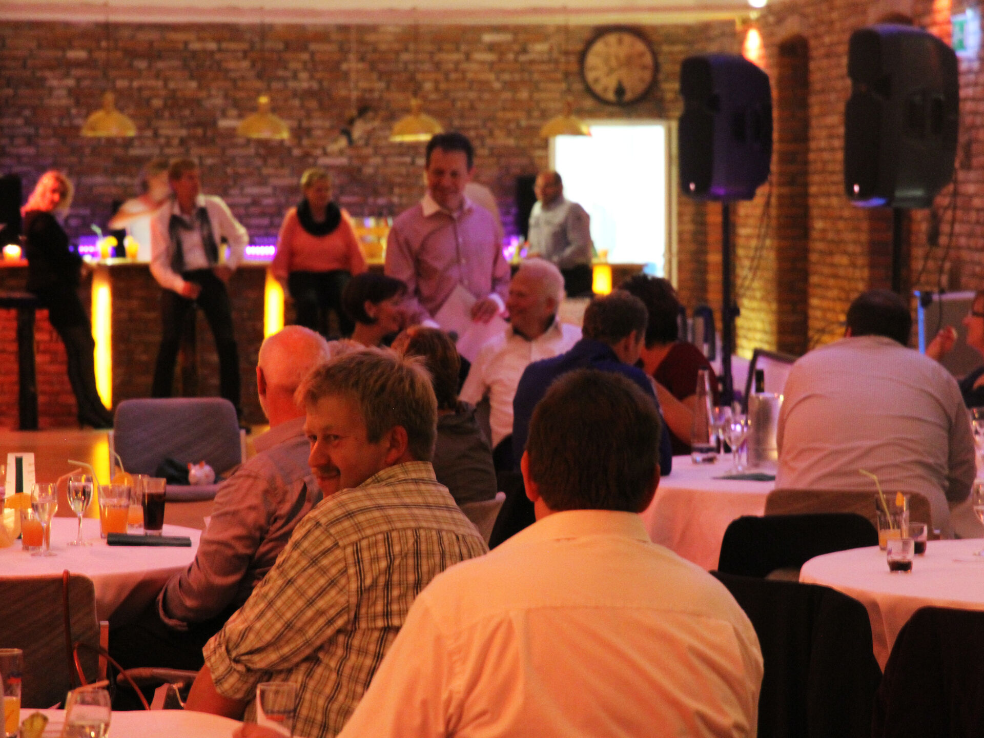 Gesellschaft in Scheune, Sicht auf Bar im Hintergrund, Verschiedene Männer im Vordergrund