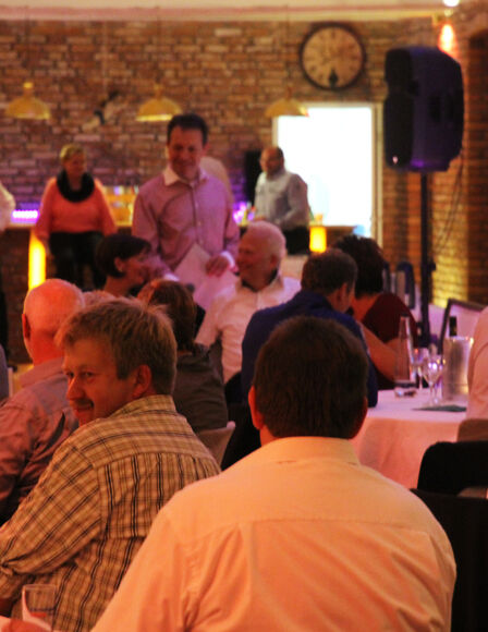 Gesellschaft in Scheune, Sicht auf Bar im Hintergrund, Verschiedene Männer im Vordergrund