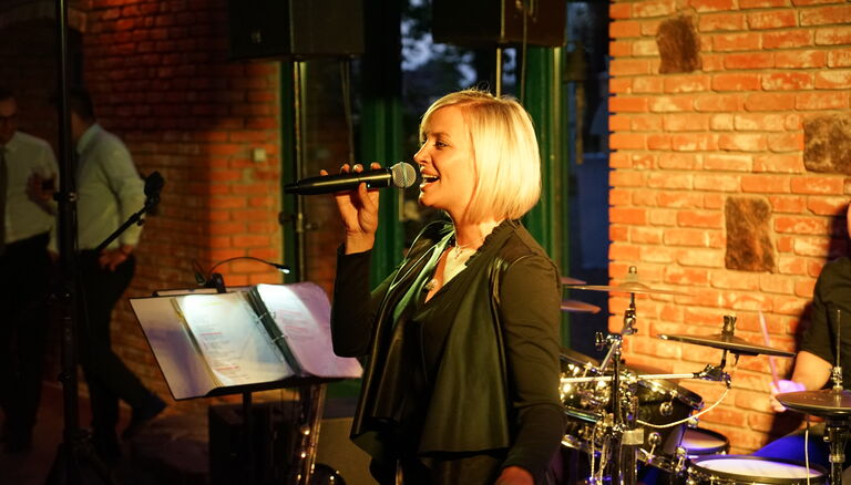 Sängerin singt in Eventscheune. Im Hintergrund ein Schlagzeug.